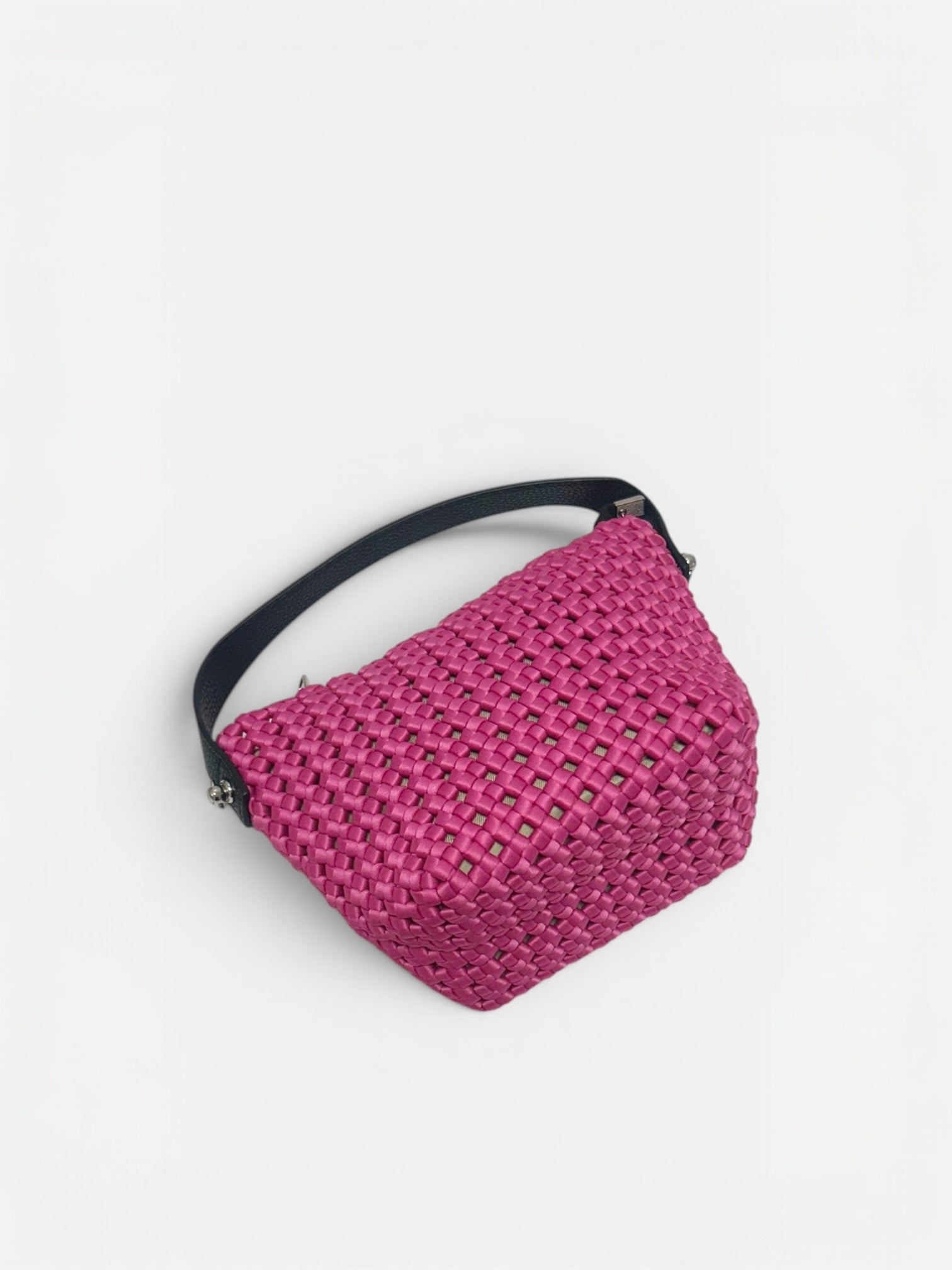 Mini borsa a secchiello Elia intrecciata di color fucsia appoggiato nella superficie